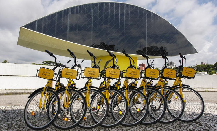 bicicletas de aluguel posicionadas uma ao lado da outra na frente do museu oscar niemayer