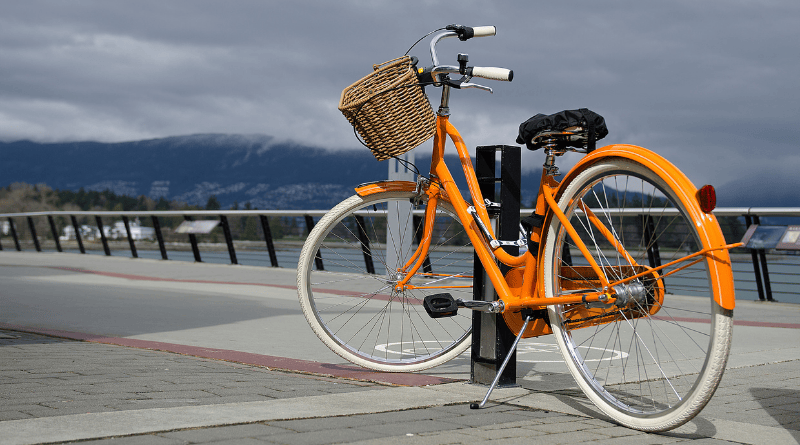 uma bicicleta amarela com cestinha e pneus brancos estacionada