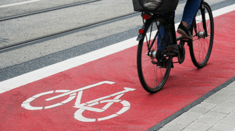 pessoa passeando por ciclovia de piso vermelho sinalizada